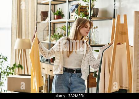 Une jeune femme trie ses vêtements pour faire don, favorisant la durabilité. Banque D'Images