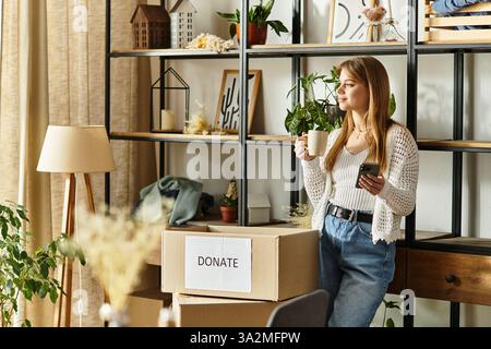 Une jeune femme trie des vêtements pour don, incarnant un mode de vie durable à la maison. Banque D'Images