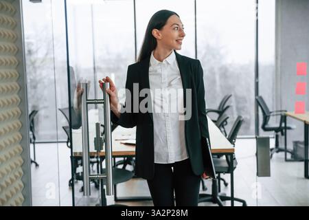 Debout et posant. Femme d'affaires est à l'intérieur dans le bureau. Banque D'Images