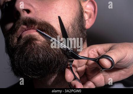 Homme avec des ciseaux de barbiers. L'homme coupe les cheveux avec des ciseaux de coiffure. Coupe de cheveux pour hommes dans une barbershop. Ciseaux de barbier. Coupe de cheveux pour hommes. Ciseaux de coiffeur Banque D'Images