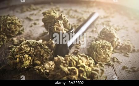 Fleurs de chanvre de cannabis séchées pour fumer riches en CBD sur une plaque en bois avec une pipe à fumer, vue rapprochée Banque D'Images