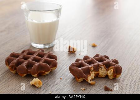 Dégustez des gaufres belges au chocolat et un verre de lait sur une table en bois. Banque D'Images