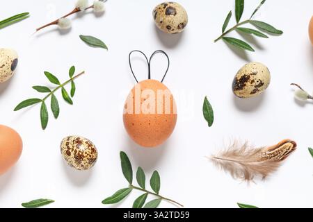 Composition avec des œufs de Pâques et des feuilles de plantes sur fond clair Banque D'Images