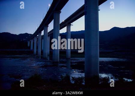 Comté de Gurye, Corée du Sud - 3 octobre 2021 : une série de piliers de pont imposants s'étendent sur la rivière Seomjin au crépuscule, illuminés par la rue Banque D'Images
