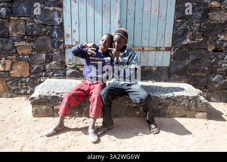 Dakar, Sénégal – deux garçons de l’île de Gorée partagent un moment ludique sur un banc de pierre, offrant un aperçu de l’enfance sur cette île historique. Banque D'Images