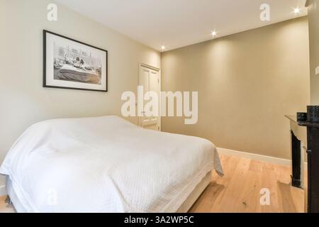 Une chambre moderne minimaliste avec un lit confortable avec des draps blancs, des luminaires élégants et des tons de couleurs douces, créant une atmosphère sereine. Banque D'Images