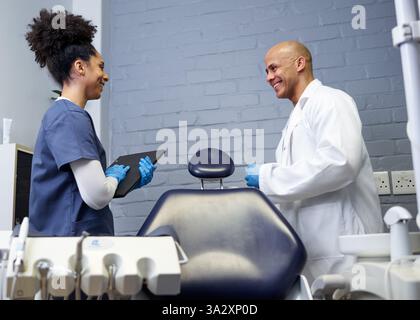 Interaction amicale entre dentiste et assistant dans un cabinet dentaire moderne Banque D'Images