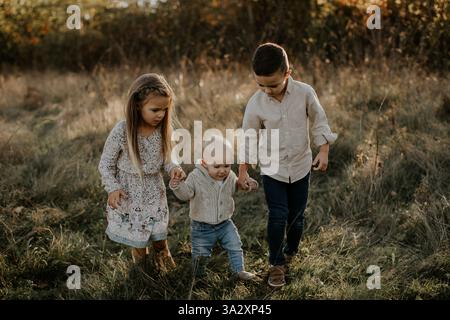 Les frères et sœurs plus âgés aident leur plus jeune frère à marcher Banque D'Images