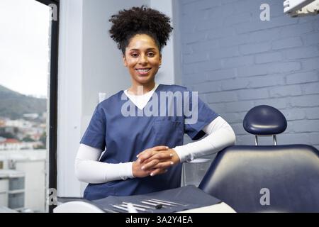 Dentiste souriant en uniforme Blue Scrub debout dans une clinique dentaire moderne Banque D'Images