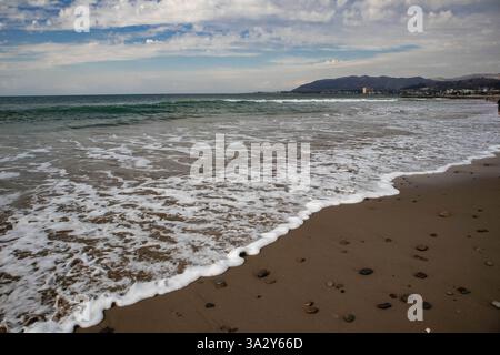 De douces vagues se jettent sur le rivage sablonneux avec Ventura City, Californie. Banque D'Images