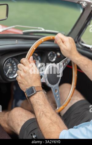 Homme tenant un volant en bois dans un cabriolet vintage Banque D'Images
