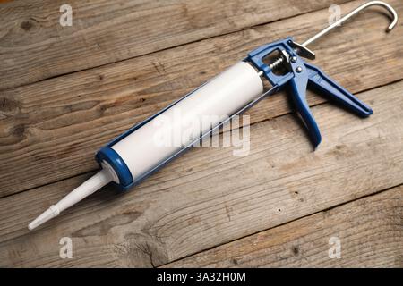 Un pistolet à colle sur fond en bois. Outil de construction Banque D'Images