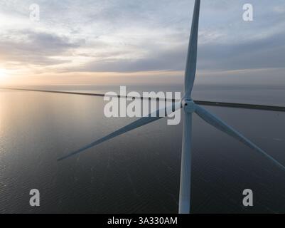 Éolienne au coucher du soleil, parc éolien offshore, énergie renouvelable, vue rapprochée. Lames, eau, paysage. Vue aérienne. Banque D'Images