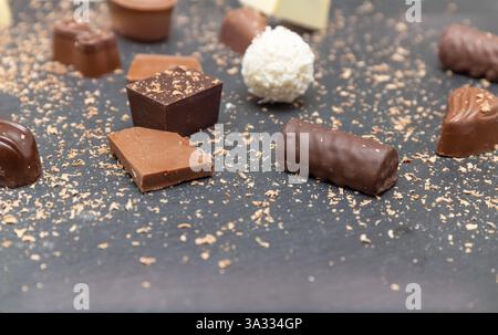 Chocolats et morceaux de chocolat au lait sur une assiette noire en pierre Banque D'Images