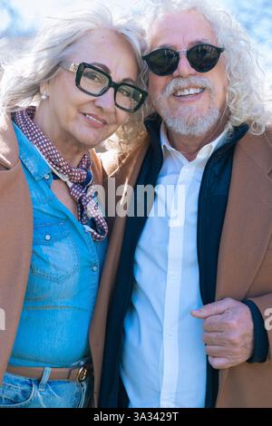 Heureux couple senior souriant à la caméra, profitant d'une journée ensoleillée à l'extérieur. Vertical Banque D'Images