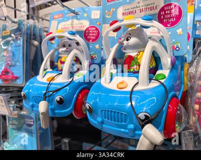 Bobruisk, Biélorussie - 2 mars 2025 : des voitures jouets aux couleurs vives avec des figurines animales ludiques sont soigneusement disposées sur les étagères des magasins. Banque D'Images