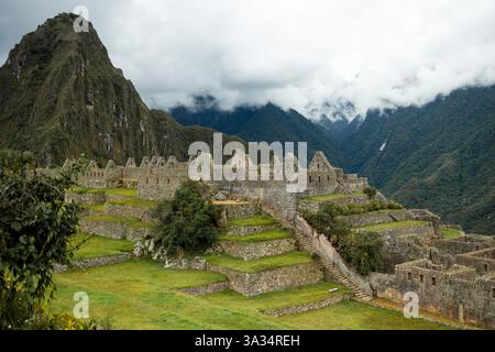 Une vue sereine sur Machu Picchu, un site classé au patrimoine mondial de l'UNESCO entouré d'une végétation luxuriante et d'une montagne brumeuse en toile de fond, incarnant l'ancienne civilisation inca Banque D'Images