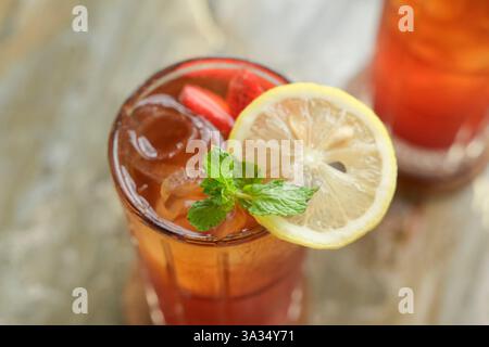 Un es Teh Nusantara fraîchement préparé avec du thé spécial Sategedhe et du sirop, élégamment garni de tranches de citron, de fraise et d'un brin de M. Banque D'Images