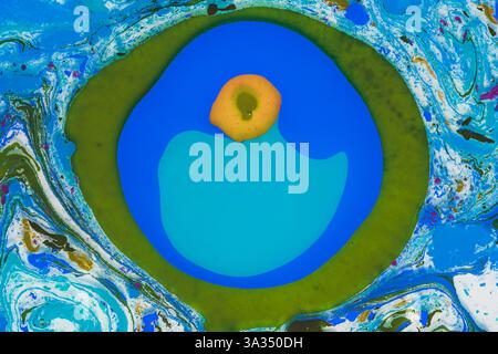 Une image abstraite présentant un mélange vibrant de couleurs bleues, vertes et blanches avec un cercle bleu audacieux et un point jaune central. Banque D'Images