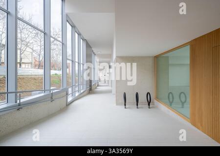 Un couloir spacieux avec de grandes fenêtres éconergétiques, avec un intérieur minimaliste, des éléments de design durable et des accents de bois naturel. Offe Banque D'Images