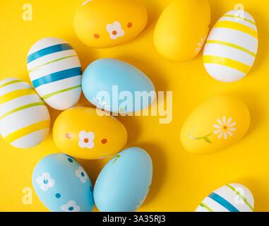 Affiche de Pâques. Œufs de Pâques bleus, jaunes et blancs sur fond jaune. Banque D'Images