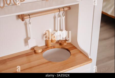 Un ensemble de cuisine en bois superbement conçu dans une chambre de fille confortable, avec des ustensiles de jeu Banque D'Images