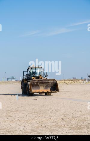 Cette machine de terrassement bulldozers déplace le sable de mer sur la plage par une journée ensoleillée Banque D'Images