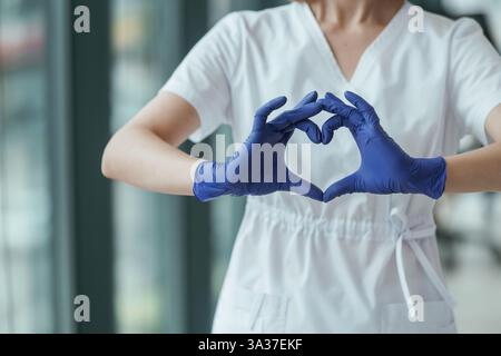 Médecin féminin montrant un geste cardiaque par les mains, vue rapprochée. Banque D'Images