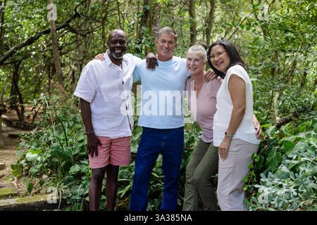 Groupe souriant d'amis seniors profitant de la nature marcher ensemble dans la forêt verdoyante Banque D'Images
