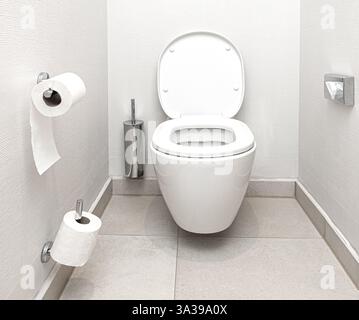 Propre et nouvelle cuvette de toilette avec couvercle ouvert et rouleaux de papier toilette dans une salle de bains moderne Banque D'Images