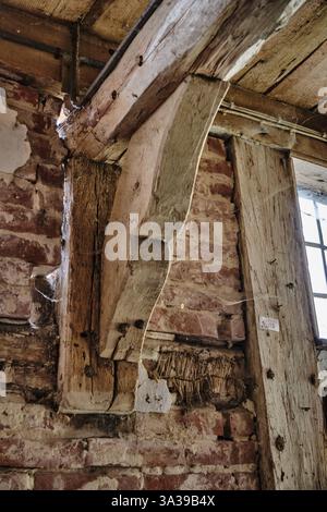12 mars 2025 - Hoya-Allemagne : poutres en bois vieilli, genouillère ornementale, murs de briques et plâtre usé à l'intérieur d'un moulin à eau historique abandonné. Banque D'Images