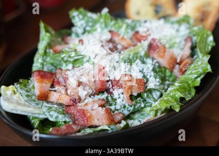 Salade avec tranches de bacon servie dans un bol, sur la table Banque D'Images