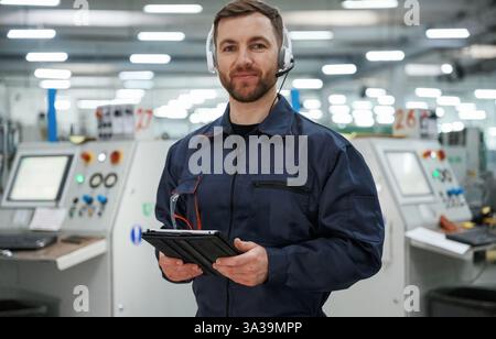 Portrait de travailleur d'usine qui est à l'intérieur avec des écouteurs. Banque D'Images