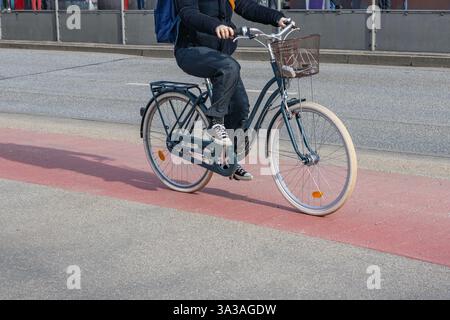 femme roule sur la piste cyclable rouge et jette de l'ombre derrière Banque D'Images