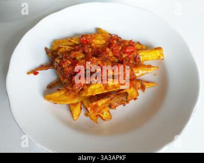 Nourriture indonésienne Minangkabau Teri Kentang balado ou anchois séchés frits et pommes de terre au piment rouge sambal balado, servis sur une assiette blanche Banque D'Images