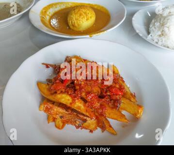 Nourriture indonésienne Minangkabau Teri Kentang balado ou anchois séchés frits et pommes de terre au piment rouge sambal balado, servis sur une assiette blanche Banque D'Images