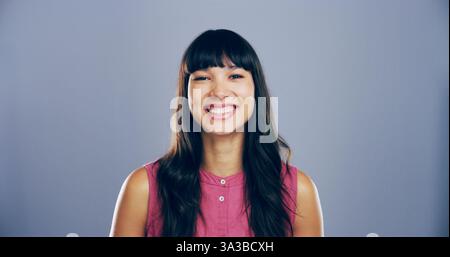 Femme heureuse, portrait et expression avec une émotion positive ou joyeuse sur fond de studio. Visage, personne féminine ou modèle avec le sourire pour décontracté Banque D'Images