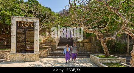 Les visiteurs portant des sarongs marchent dans le jardin du temple Uluwatu (Pura Luhur Uluwatu). Péninsule de Bukit, Bali, Indonésie. Banque D'Images