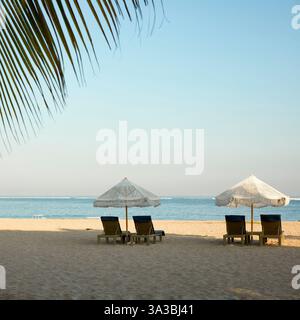 Chaises longues sous parasols blancs sur Jerman Beach. Kuta, Bali, Indonésie. Banque D'Images