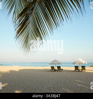 Chaises longues sous parasols blancs sur Jerman Beach. Kuta, Bali, Indonésie. Banque D'Images