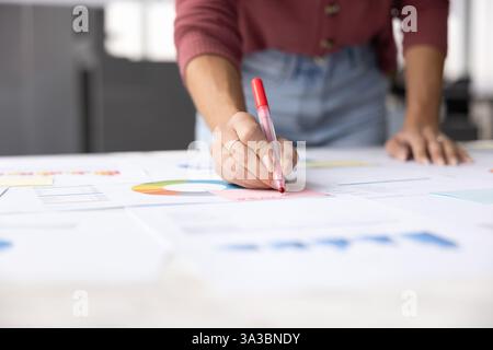 Plan recadré du chef de projet écrivant des notes sur des rapports papier Banque D'Images