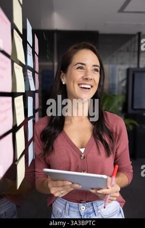 Joyeuse belle jeune femme latine tenant la tablette Banque D'Images