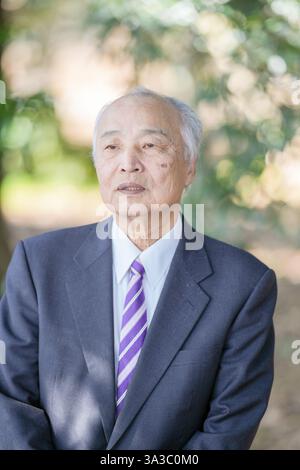 Un parc sur une agréable journée de printemps avec beaucoup de verdure au Japon. Un Japonais à la fin des années 70 portant un costume se lève. Banque D'Images