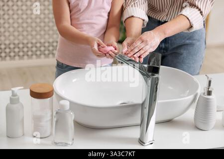 Mère et fille se lavant les mains à l'intérieur, gros plan Banque D'Images