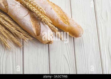 Deux baguettes et épis de blé sur vieilles planches de bois blanc avec copyspace Banque D'Images
