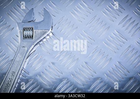 Clé réglable en acier inoxydable sur concept de construction de plaque métallique rainurée Banque D'Images