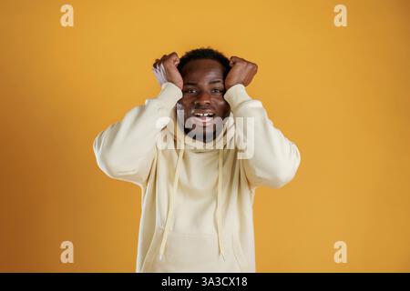 Expression faciale choquée surprise. Black Guy est sur fond jaune. Banque D'Images