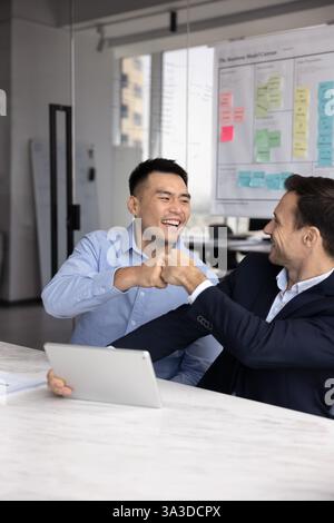 Deux partenaires commerciaux et amis heureux et diversifiés jouissant d'un travail d'équipe efficace Banque D'Images