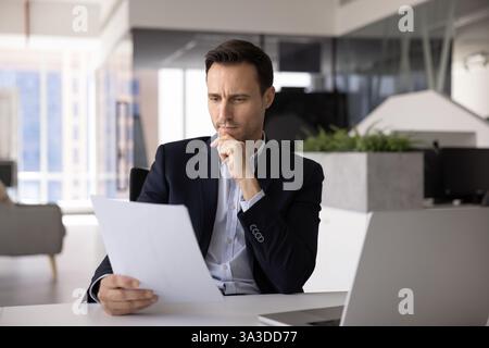 Pensif concerné homme d'affaires hispanique expert juridique lisant un document financier Banque D'Images
