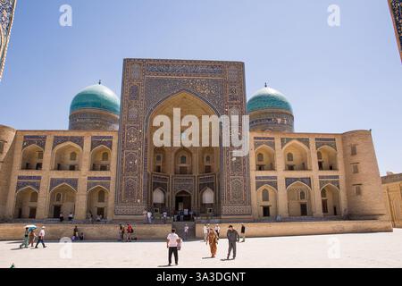 Boukhara, Ouzbékistan - 09 juillet 2024 : Mir-i Madrasa arabe, pendant la journée et avec des touristes sur la place de Boukhara Banque D'Images
